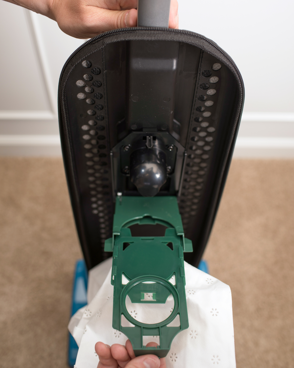 Person installing a green bag dock onto a vacuum cleaner.