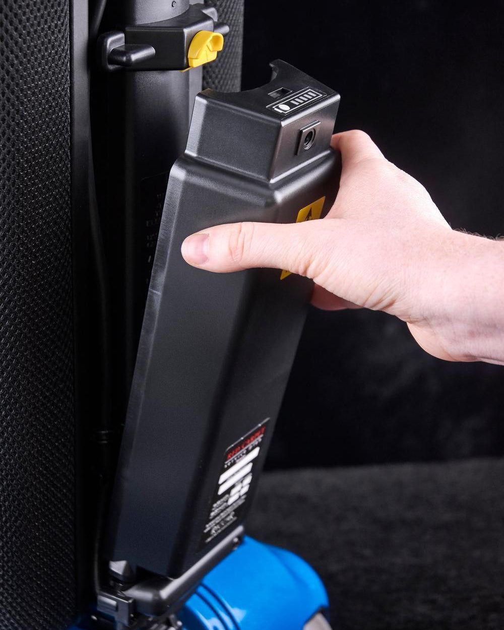 Hand connecting a black battery pack to a vacuum's charging system.