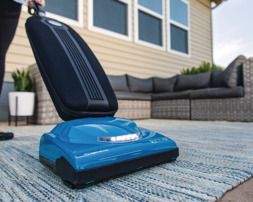 Blue vacuum cleaner on a patio with a house in the background