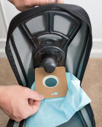 Person installing a cardboard fitting paperbag onto a vacuum cleaner bag dock.