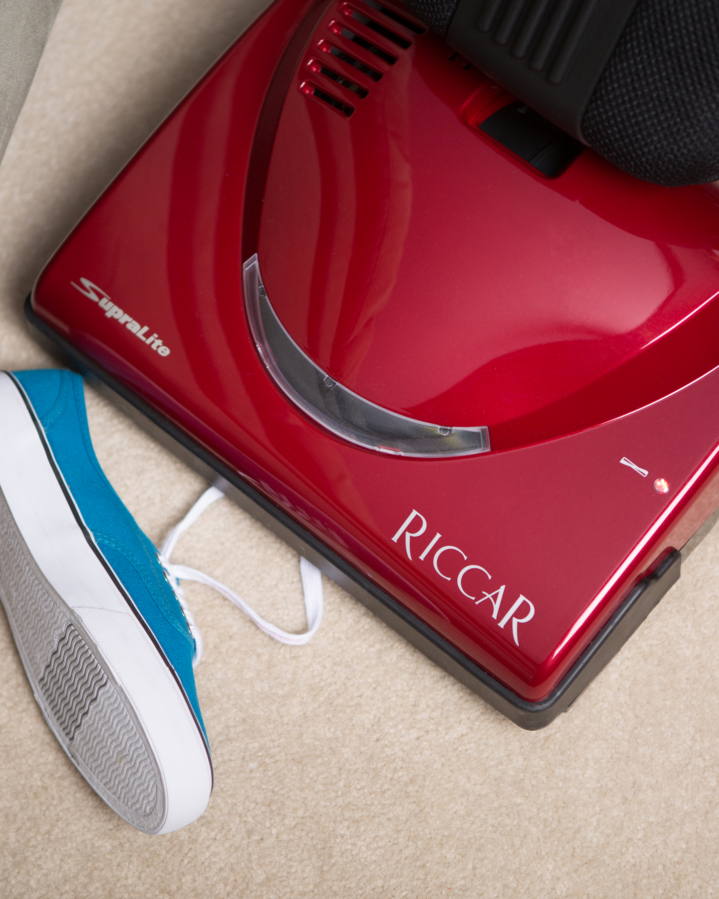 Red Riccar R10P vacuum demonstrating the automatic brush shut off features on the vacuum by vacuuming up a shoelace.
