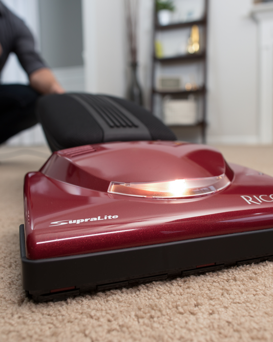 Red Riccar R10P vacuum cleaner on a carpet with a person demonstrating how the vacuum lays completely flat.